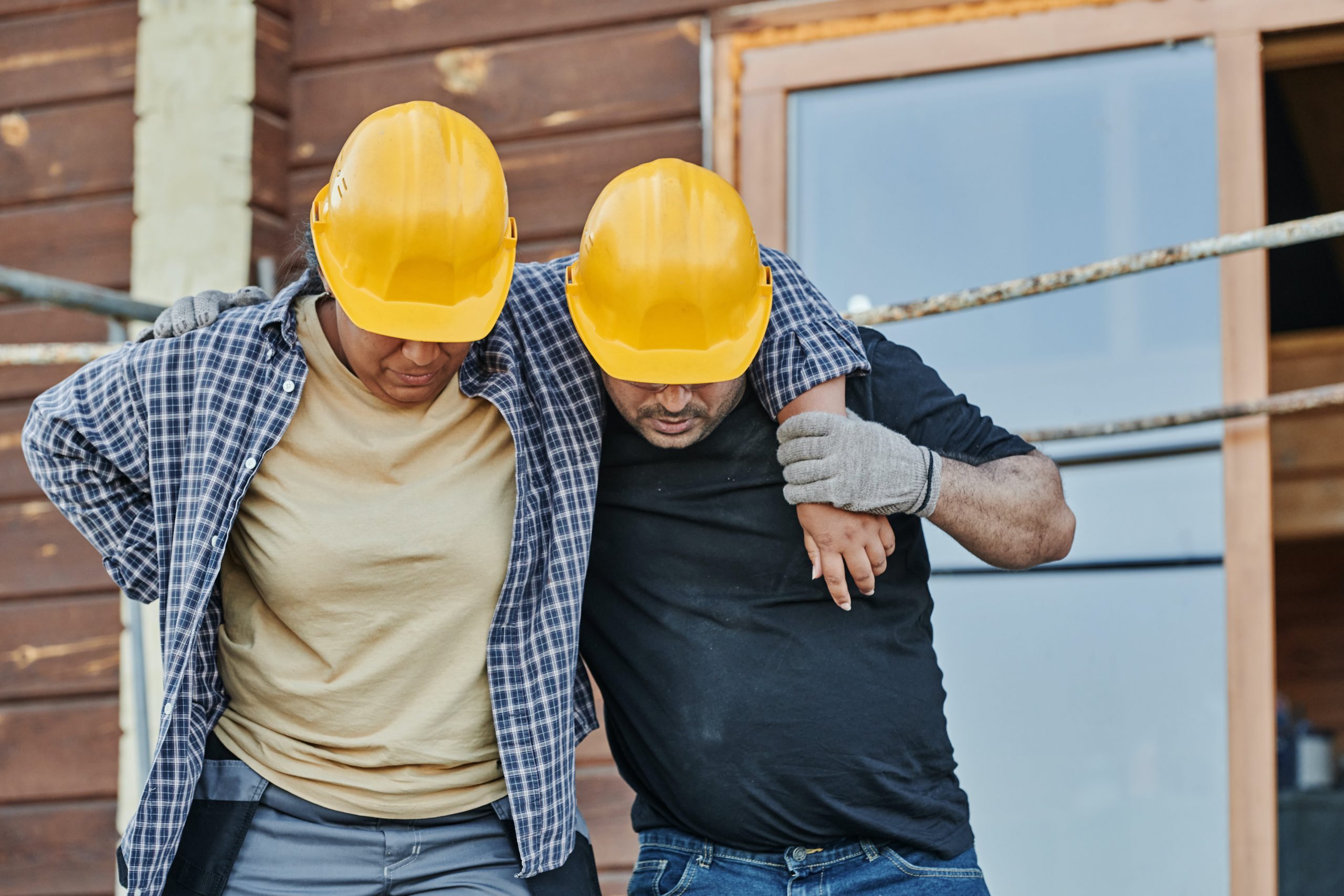 construction worker helping another worker walk after back injury