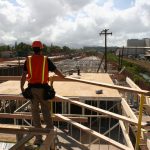 construction worker standing at guardrail system overlooking construction site